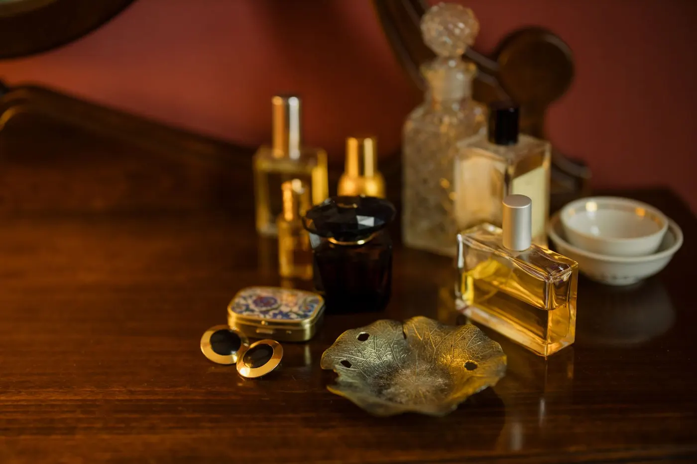 A collection of perfume bottles on a wooden dressing table in warm light