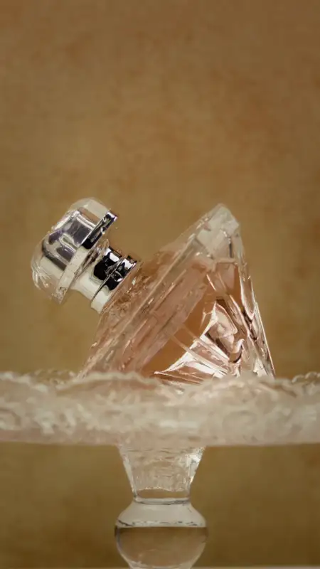 A crystal perfume bottle with liquid pouring over it